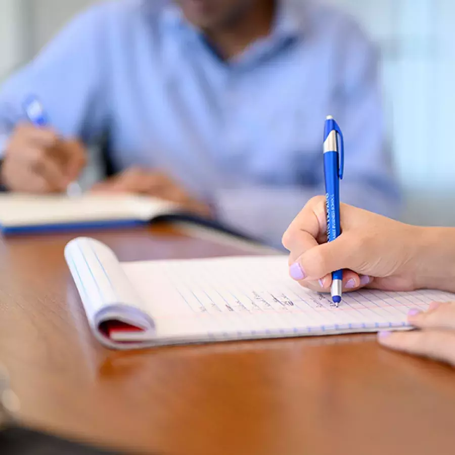 two students sitting at a table writing on a notepad