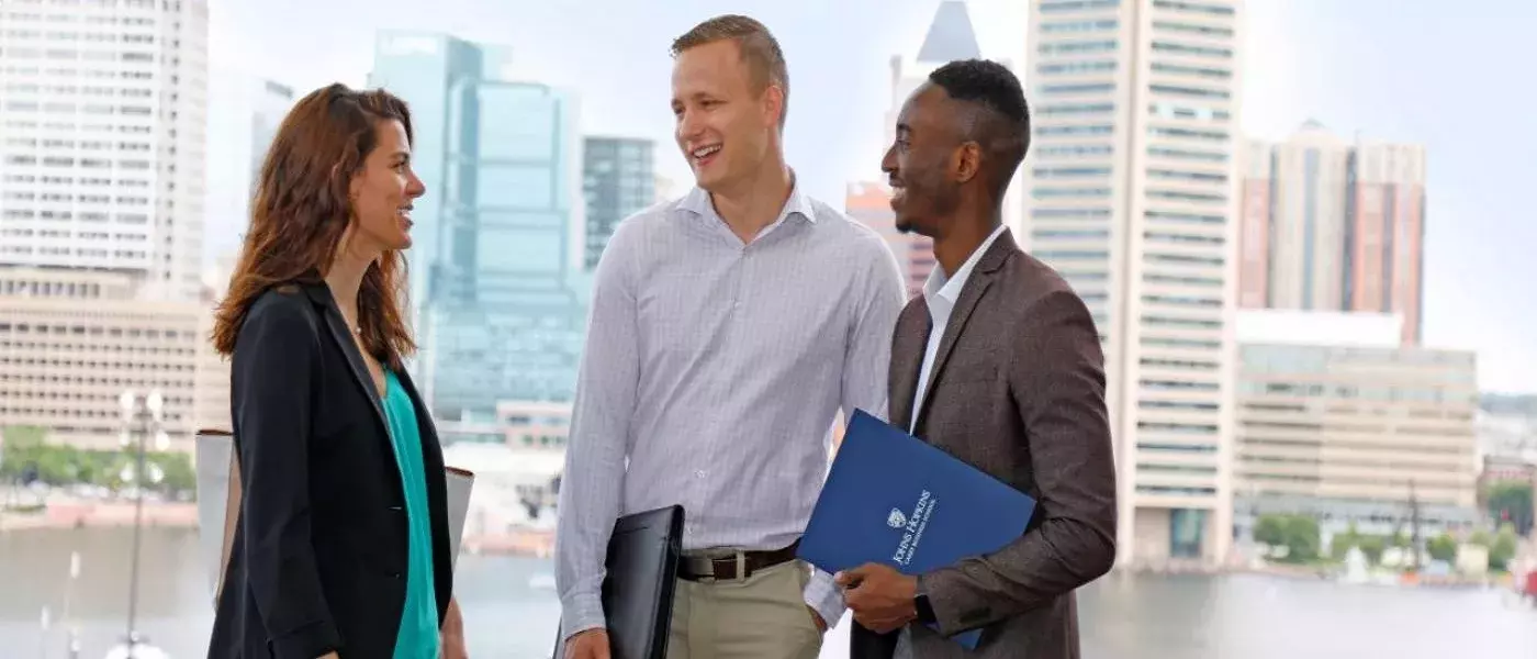 three students standing in front of downtown Baltimore